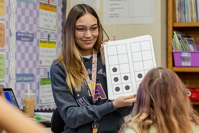 Student teacher shows paper to student