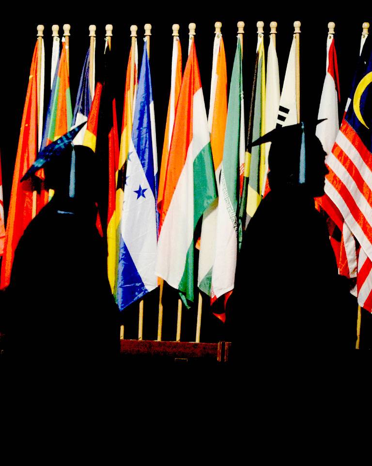 Graduates walking in front of flags