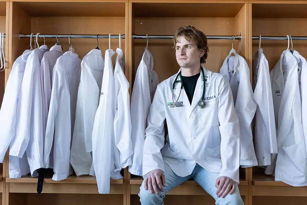 Carson Herbert standing in front of medical coats