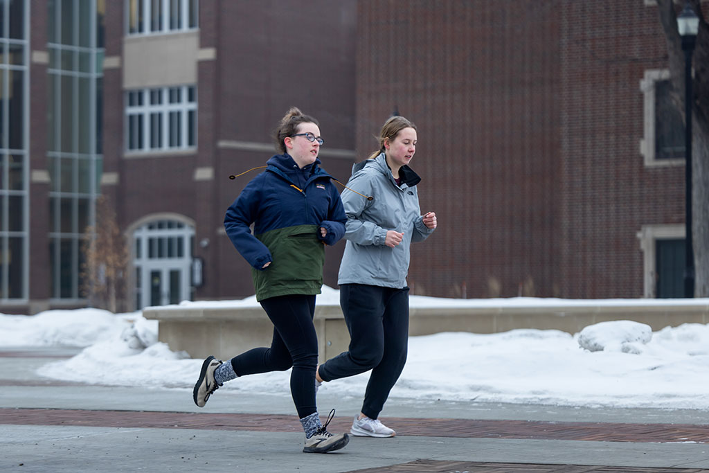Two women running on campus