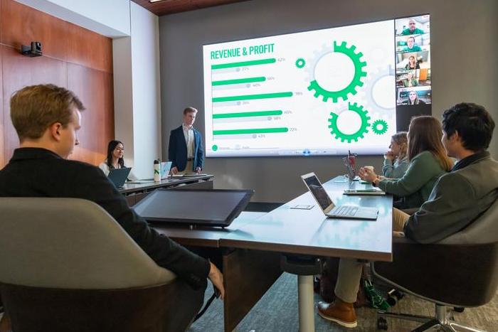 Group around table talking with screen behind.