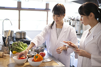 Two ladies cooking in white chef coats