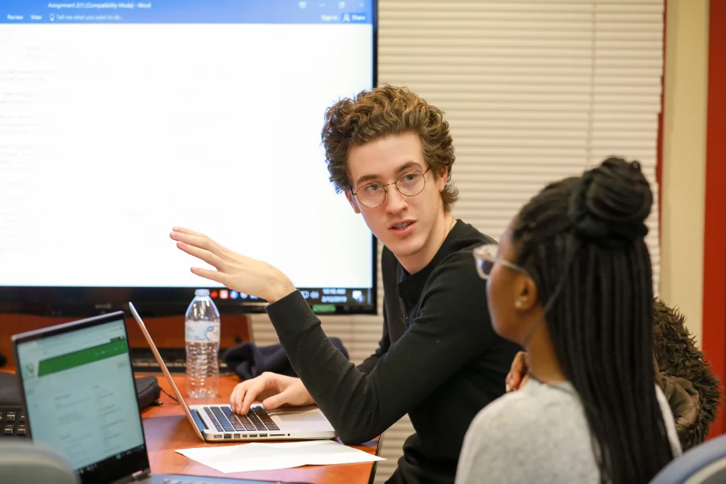 Two psychology students in the campus library work together on their new project, discussing their latest research