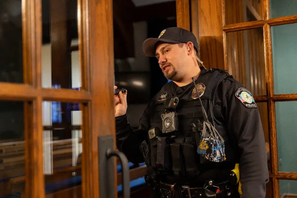 A DEA agent at a crime scene, using a flashlight while opening a door