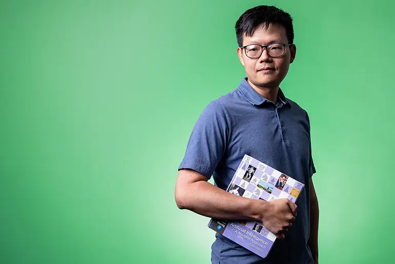 Harry Zou posing with book on UND campus
