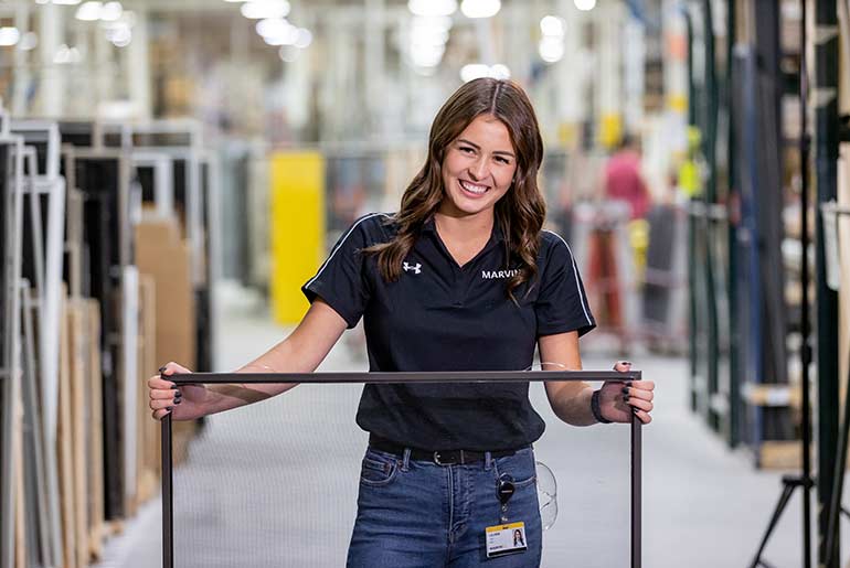 Lauren Cain holding a window screen working at Marvin Windows and Doors