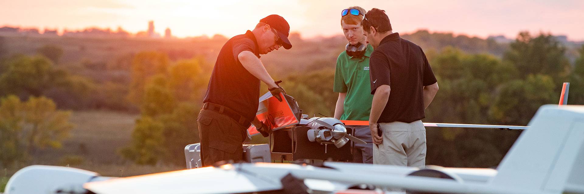 three people working on uas at sunset