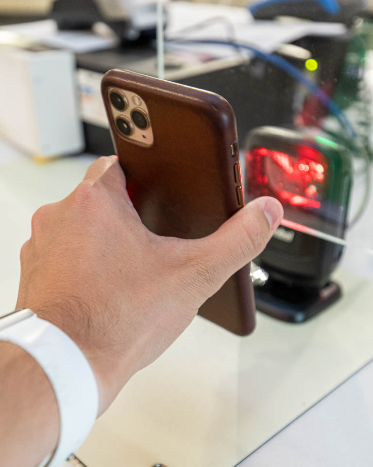 a hand holding a iphone that is being scanned at the checker stand to enter the dining center