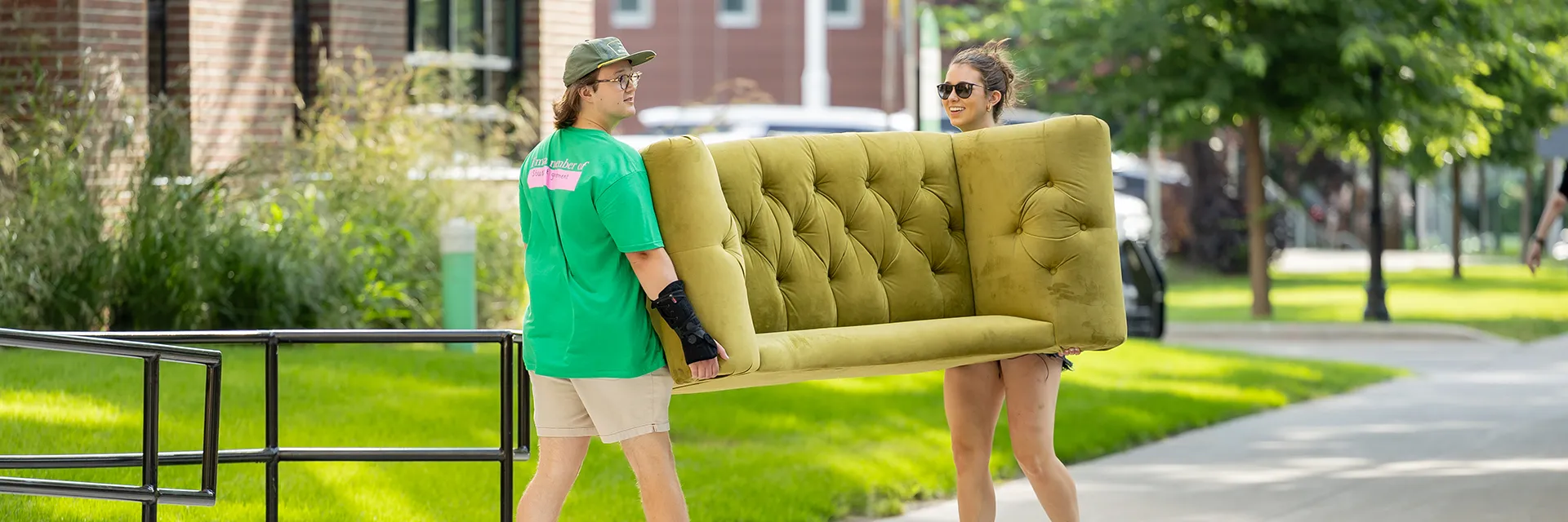 two students carry a couch into residence hall