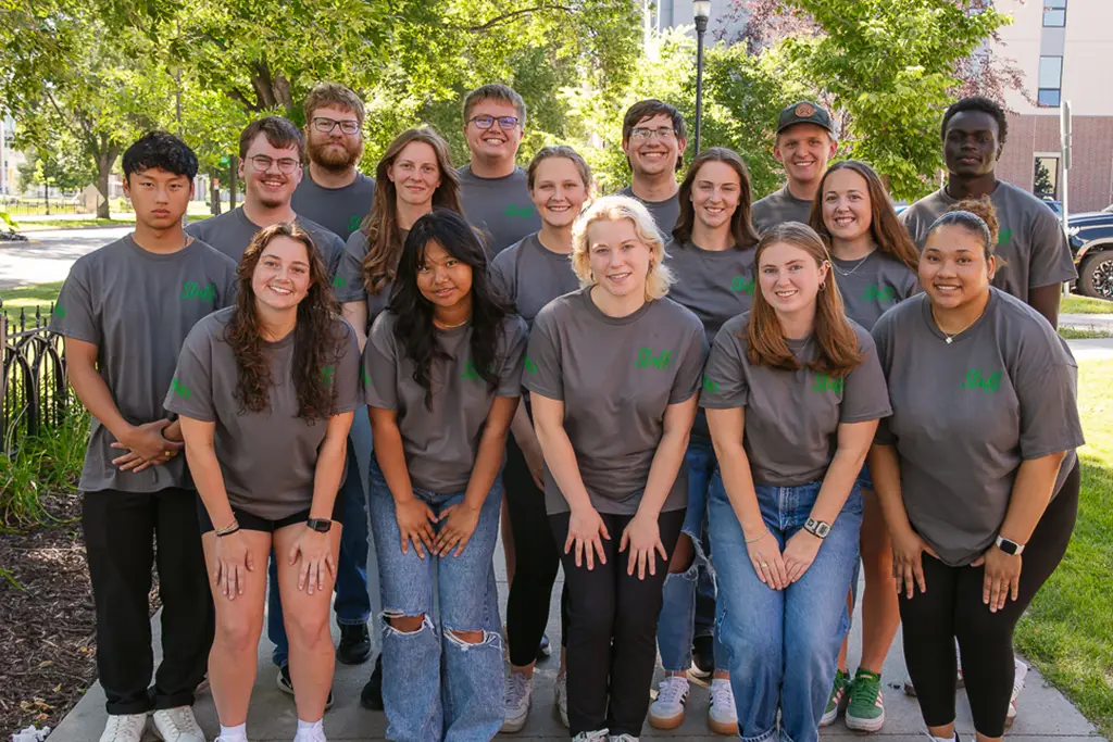 Group of young people pose for a photo with the side walk continuing behind them